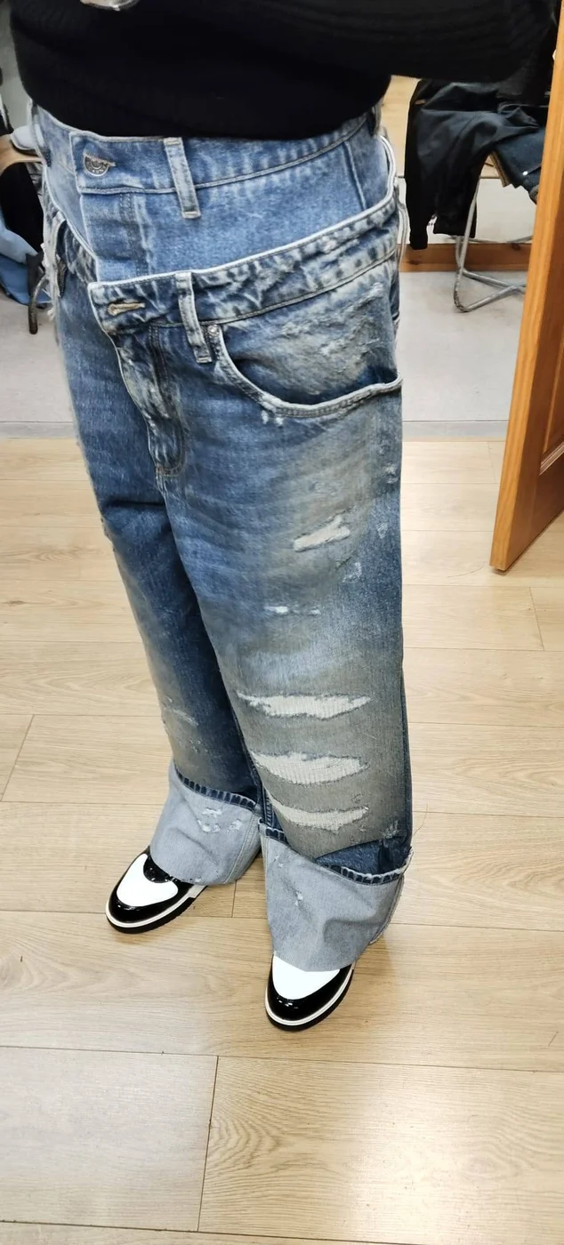 Distressed wide-leg jeans being worn with trainers
