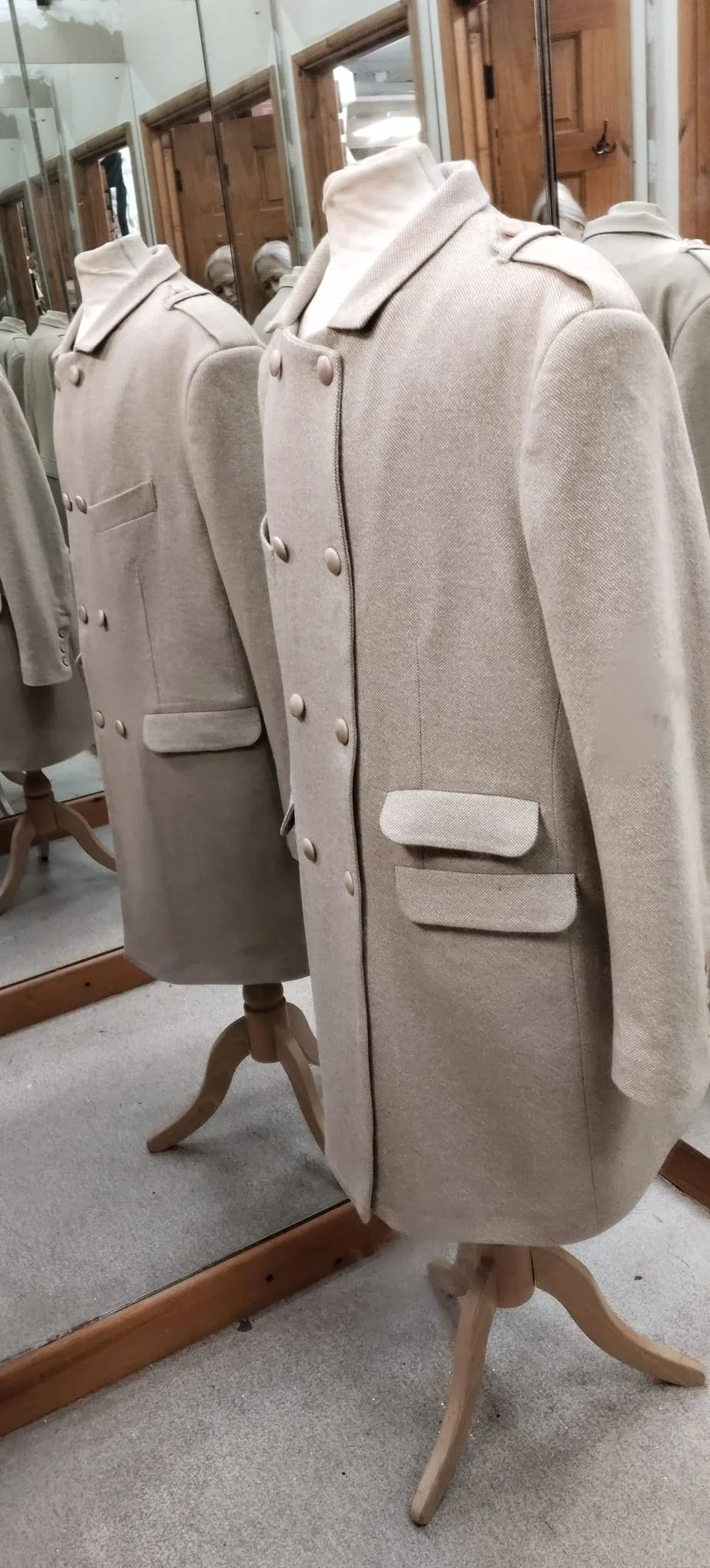 Cream double-breasted tailored overcoat displayed on a dress form